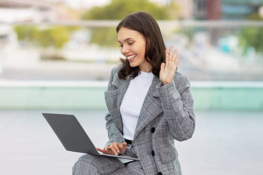 lady engaged in video call on laptop waving hand outside