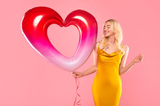 Blissful woman with vibrant heart balloon on pink background