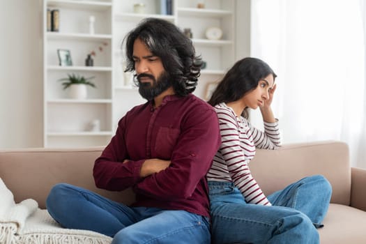 Upset young married indian couple sitting back to back