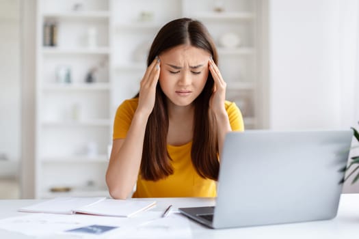 Stressed Young Asian Female Freelancer Having Headache While Working In Home Office