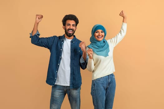 Joy Of Win. Happy Excited Muslim Couple Celebrating Success With Raised Fists