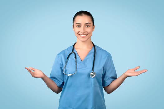 Smiling female nurse with open palms in blue uniform