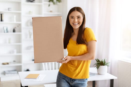 Joyful Young Asian Female Holding Big Cardboard Box At Home