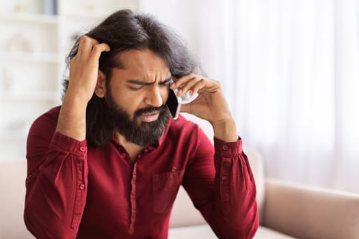 Upset distressed indian guy have phone conversation, home interior