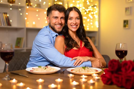 Happy couple embracing at dinner with wine and roses, warm bokeh lights