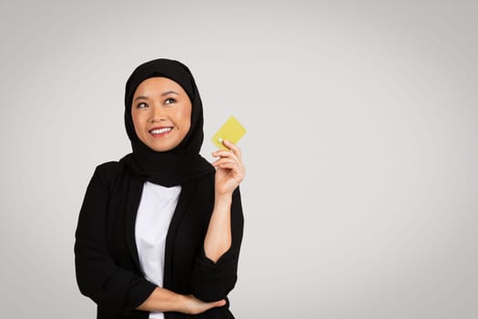Pensive happy young asian woman in suit, hijab think, look at empty space