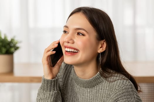 Closeup of happy young woman talking on phone at home