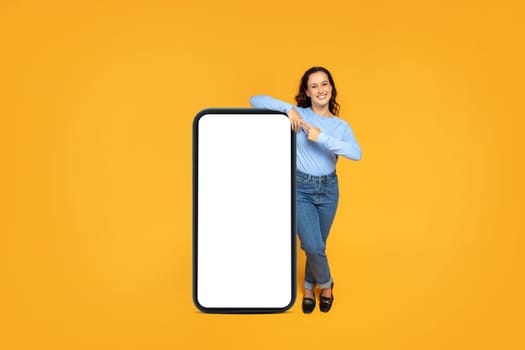 Positive attractive lady posing with big smartphone with empty screen