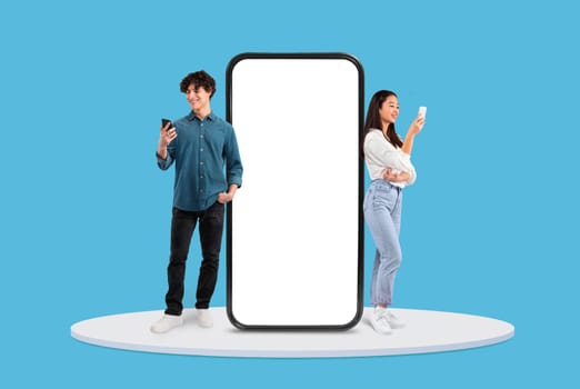 Young man and woman with phones by large blank display