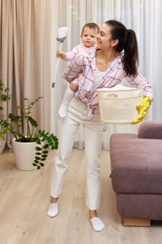 mother housewife is holding baby and doing housework