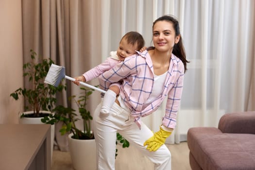 mother housewife is holding baby and doing housework