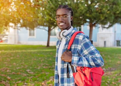 Portrait of confident black student with headphones and backpack outdoor