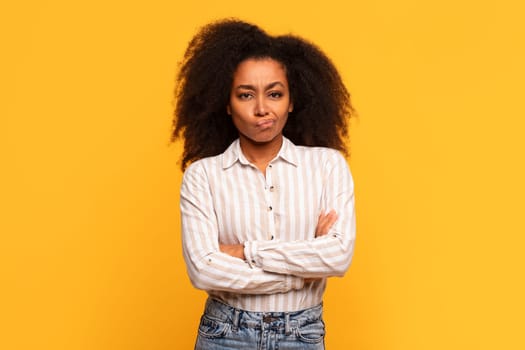 Skeptical black lady with arms crossed on yellow background