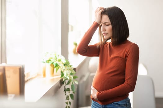 Young pregnant lady suffering from migraine and flu symptoms indoors