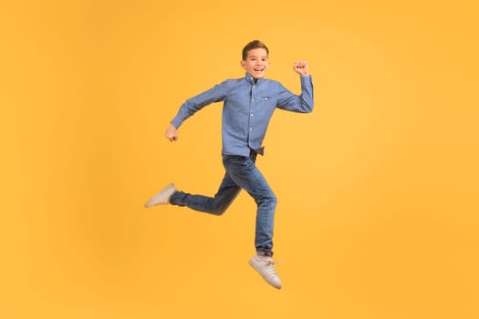 Dynamic teen boy jumping in air against yellow studio background