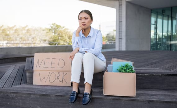 Depressed Asian businesswoman with belongings and poster Need Work outside