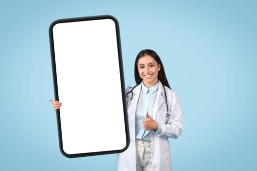 Positive female doctor with thumbs up holding huge mobile screen