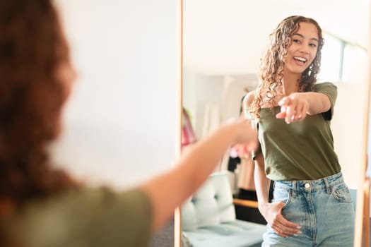 caucasian teenager girl pointing at herself in mirror at home