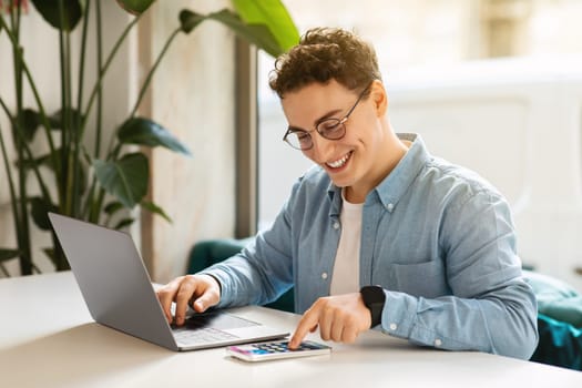 Happy young european guy student in glasses, typing on smartphone