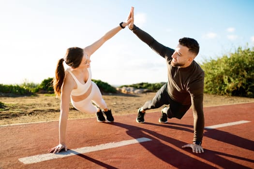 Couple giving high-five during side plank workout
