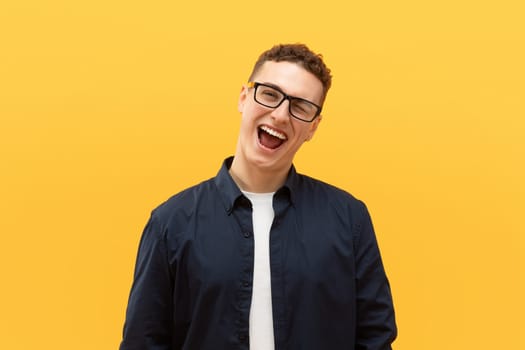 Playful young blonde guy posing on yellow background