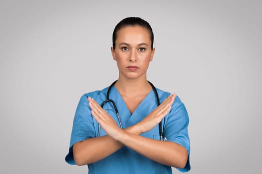 Stern nurse with crossed arms in blue scrubs