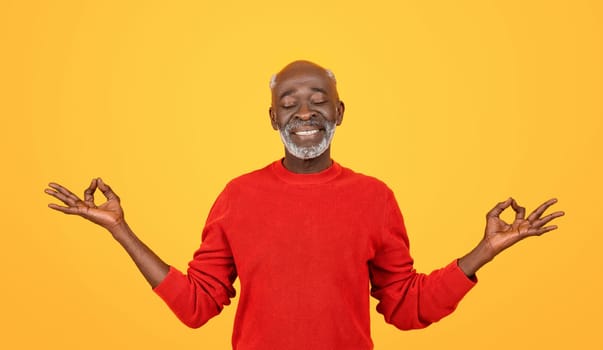 Blissful senior Black man with a white beard, eyes closed and hands in a yoga mudra