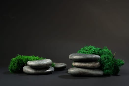 Stones decorated with green moss against black background