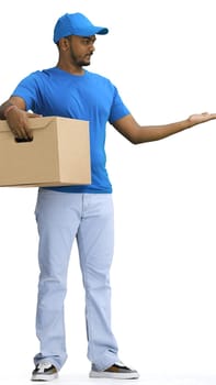 A male deliveryman with a box, on a white background, in full height, points to the side