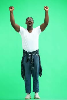 A man with a shirt tied at his waist on a green background waves his hands