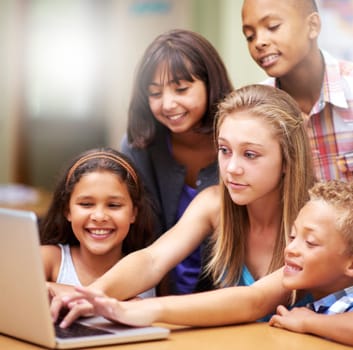 Young tutor, laptop and teaching children. kids or pupils technology, social media or research in class. Group of elementary students with mentor showing tech, internet or online search in classroom