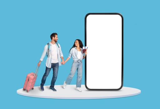 Happy couple with luggage walking past large phone display