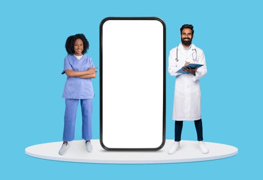 Confident nurse and doctor with clipboard beside huge vertical smartphone screen, ideal for healthcare app promotions, on blue backdrop, mockup
