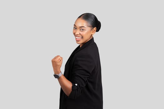 Energetic African American businesswoman with a beaming smile makes a fist pump gesture