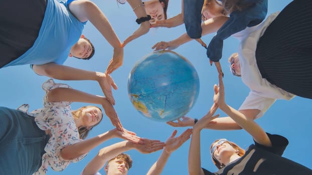 Young friends surround the globe of the world with their palms. The concept of preserving world peace.