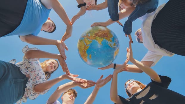 Young friends surround the globe of the world with their palms. The concept of preserving world peace.