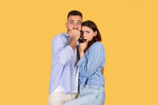 Surprised couple with man covering his mouth and woman looking shocked