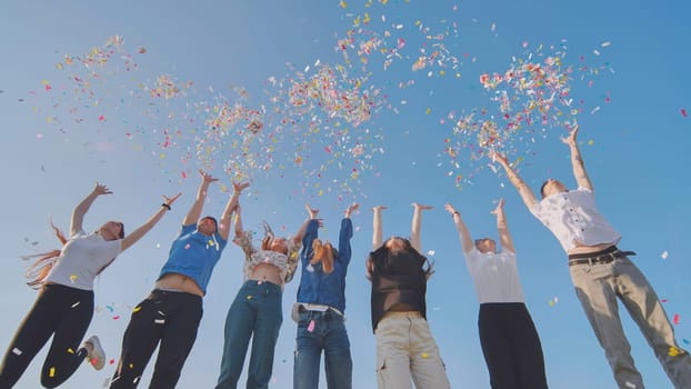 Friends toss colorful paper confetti from their hands.