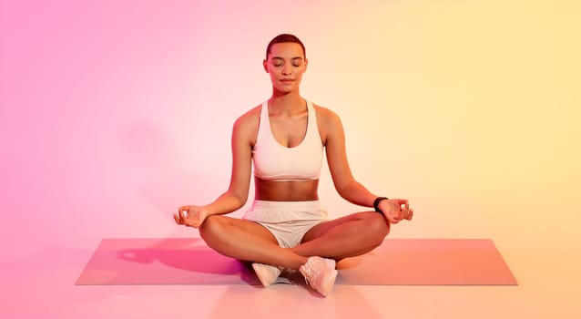 Serene young woman with a short haircut in sportswear meditating in lotus position