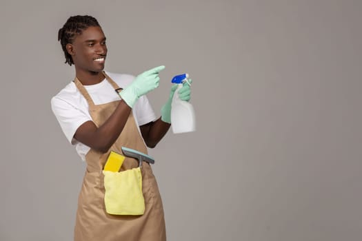 Cleaning Advertisement. Young Black Male Cleaner Holding Detergent Spray And Pointing Aside