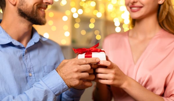 Man gifting woman a present with a bow, romantic setting