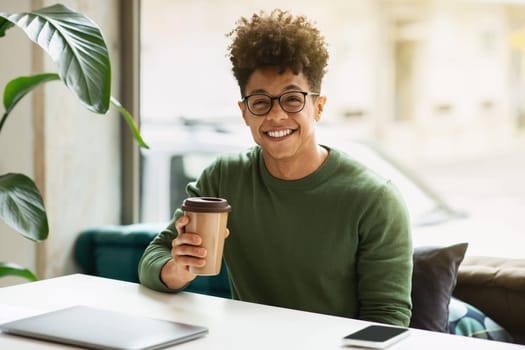 Stylish african american guy freelancer drinking coffee at cafe