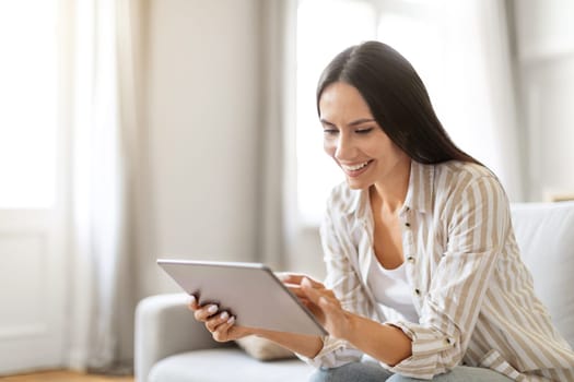Cheerful young woman engaged with her digital tablet at home
