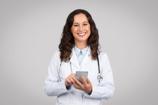 Smiling woman doctor texting on a smartphone