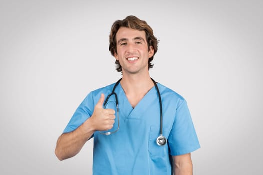 Smiling european man nurse giving thumbs up on grey background