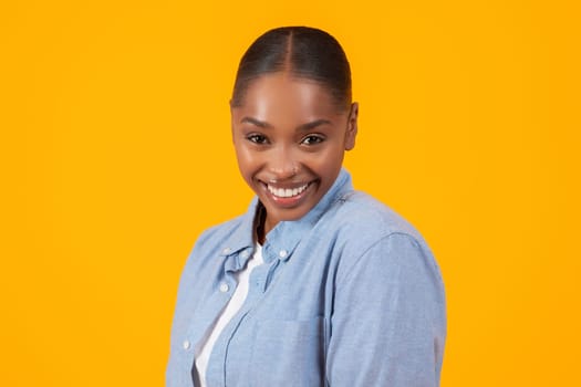 Portrait of cheerful pretty African American lady over yellow backdrop