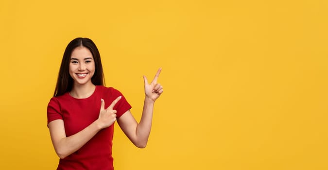 Cheerful asian woman pointing at copy space