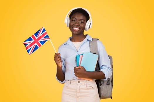 Smiling millennial african american lady student in wireless headphones, with books