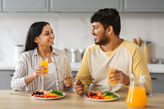 Happy attractive young indian couple have healthy dinner at home