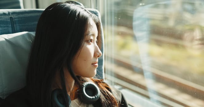 Japanese woman, window and train with headphones, travel and public transportation on metro bullet. Young person, thinking and relax on fast vehicle for weekend trip and wellness by audio technology